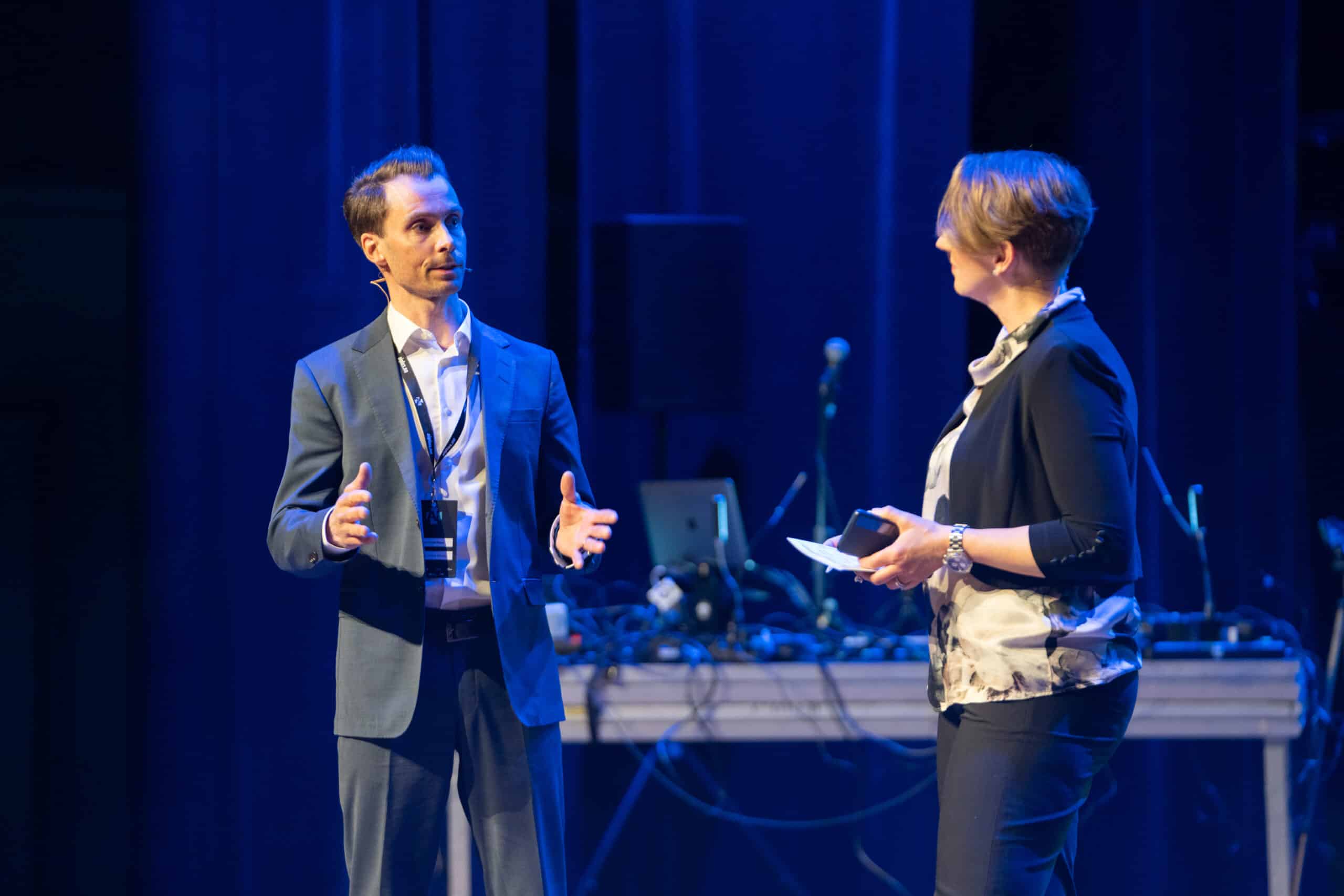 Jonas Aamodt Moræus from the AI+ partner Institute of Energy Technology talking to hostess Ruth Astrid Sæter. PHOTO: Stein Johnsen, Contentvideo.no